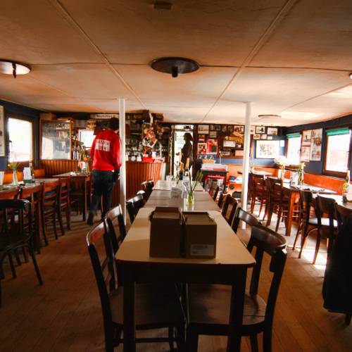 Innenansicht der Gaststätte vom Theaterschiff Batavia. Drei Tischreihen mit Stühlen.